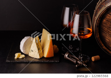 A refined selection of aged cheeses presented on a board, accompanied by a glasses of wine 122965568