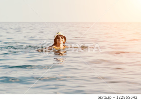 Woman Swimming Ocean Hat Summer - A woman in a hat swims in the ocean during a summer day. Woman Swimming Ocean Hat Summer - A woman in a hat swims in the ocean during a summer day. 122965642