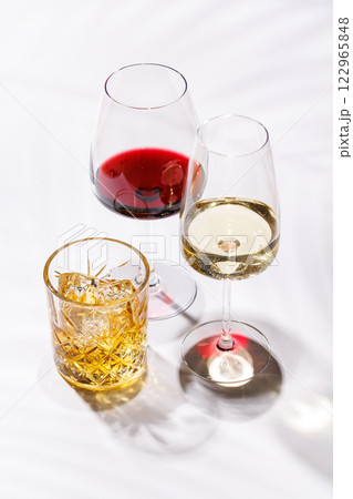 A refined composition of wine glasses filled with red and white wine, paired with a whiskey glass A refined composition of wine glasses filled with red and white wine, paired with a whiskey glass 122965848