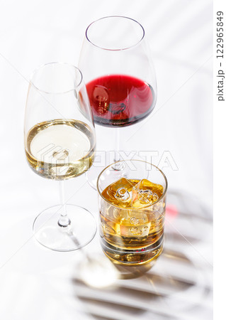 A refined composition of wine glasses filled with red and white wine, paired with a whiskey glass A refined composition of wine glasses filled with red and white wine, paired with a whiskey glass 122965849