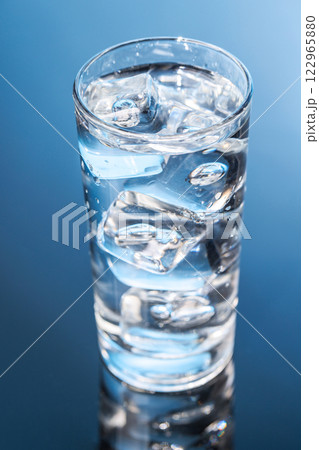 A clear glass filled with chilled water and ice cubes, creating a refreshing and cool drink A clear glass filled with chilled water and ice cubes, creating a refreshing and cool drink 122965880