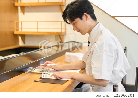 電卓で集計作業をする和食の料理人 122966201