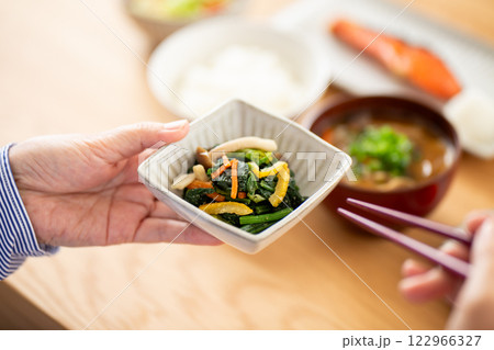 和食の朝食で野菜のおひたしを食べるミドル女性 122966327