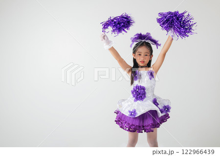 Little girl in cheerleading outfit with purple pom-poms, beaming happily in a white studio setup. A moment of fun and energy. cheerleader kid Little girl in cheerleading outfit with purple pom-poms, beaming happily in a white studio setup. A moment of fun and energy. cheerleader kid 122966439