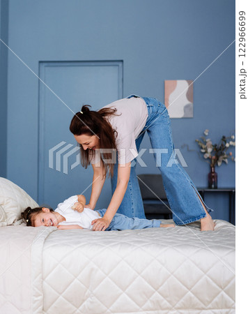 Mom plays with her daughter in the bedroom on the bed Mom plays with her daughter in the bedroom on the bed 122966699