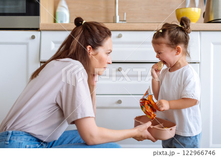Mother gives her daughter a cookie 122966746
