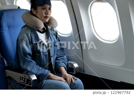 young woman travels alone on a plane and uses an eye mask young woman travels alone on a plane and uses an eye mask 122967792