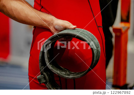 athlete powerlifter in a red singlet holds weightlifting belt behind his back athlete powerlifter in a red singlet holds weightlifting belt behind his back 122967892