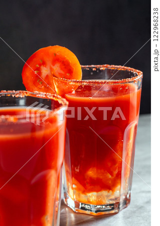 Two vegetable shaken cocktails in glass on dark grey background. Red tomato cocktail. Served with tomato slice. Vegan menu. 122968238