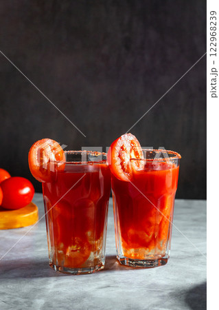 Two vegetable shaken cocktails in glass on dark grey background. Red tomato cocktail. Served with tomato slice. Vegan menu. 122968239