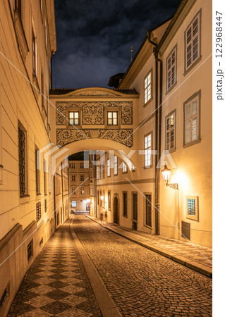 This quiet street showcases the passage bridge of the Chamber of Deputies, illuminated by soft light, framed by historic buildings along Thunovska Street in Lesser Town, Prague. This quiet street showcases the passage bridge of the Chamber of Deputies, illuminated by soft light, framed by historic buildings along Thunovska Street in Lesser Town, Prague. 122968447