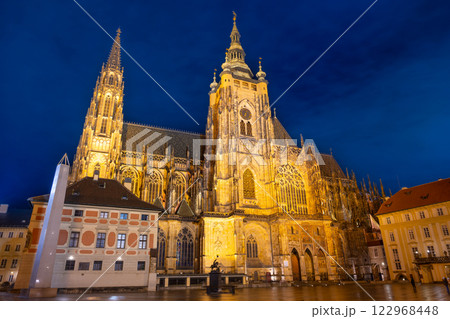 St Vitus Cathedral stands majestically illuminated at night within Prague Castle. Its intricate architecture and historic significance shine brightly against the deep blue sky. 122968448