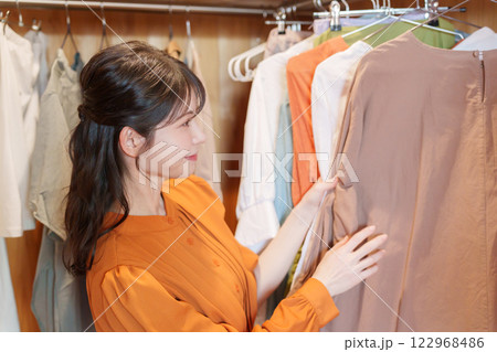 ウォークインクローゼットで服を選ぶ女性（ファッション・コーディネート） 122968486