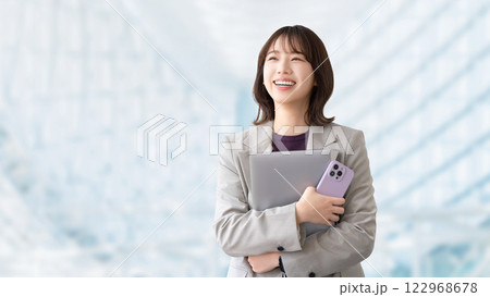パソコンとスマホを持つ笑顔の女性・ビジネスウーマン パソコンとスマホを持つ笑顔の女性・ビジネスウーマン 122968678