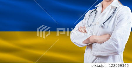 Doctor with crossed arms on Ukraine flag. Ukraine Health and Care concept. Female doctor on Ukraine flag 122969346