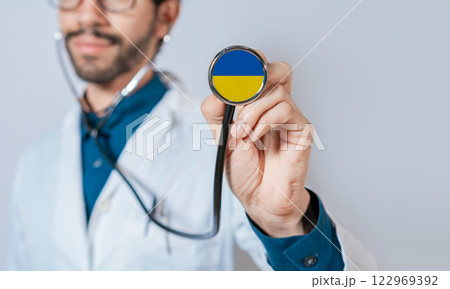 Doctor holding stethoscope with Ukraine flag. Ukraine Health and Care Concept, Ukraine flag on stethoscope Doctor holding stethoscope with Ukraine flag. Ukraine Health and Care Concept, Ukraine flag on stethoscope 122969392