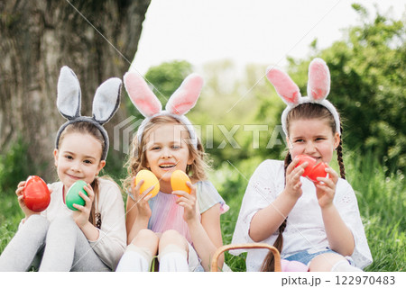 Easter egg hunt. Group Of Children Wearing Bunny Ears Running To Pick Up colorful Egg On Easter Egg Hunt In Garden. Easter tradition Easter egg hunt. Group Of Children Wearing Bunny Ears Running To Pick Up colorful Egg On Easter Egg Hunt In Garden. Easter tradition 122970483