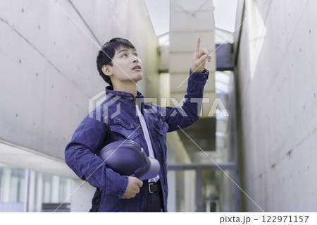 現場でヘルメットを抱えて点検する若い作業員 122971157