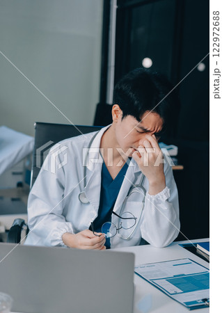 Positive doctor working on laptop in medical office, portrait. 122972688