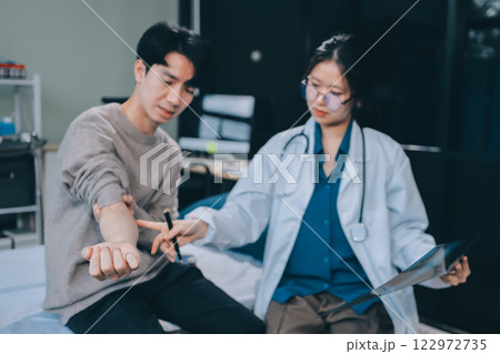 Female physician reads medical history while visiting her patient Female physician reads medical history while visiting her patient 122972735