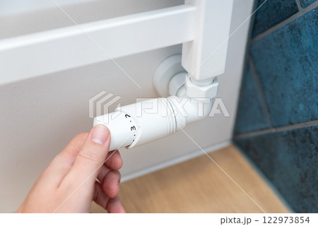 Modern white radiator, hand holding thermostat Modern white radiator, hand holding thermostat 122973854