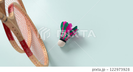 Two wooden badminton rackets and colorful feather badminton shuttlecock on blue background. View from above. Concept racket sport. Leisure games. Two wooden badminton rackets and colorful feather badminton shuttlecock on blue background. View from above. Concept racket sport. Leisure games. 122973928