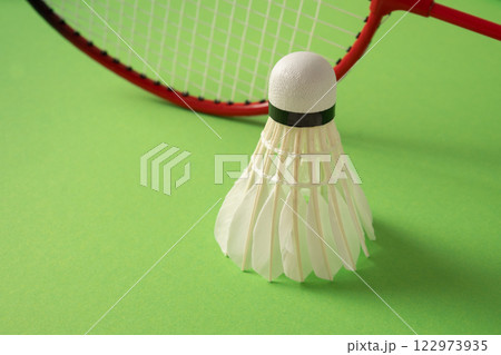 Two wooden badminton rackets and white feather badminton shuttlecock on green background. View from above. Concept racket sport. Leisure games. 122973935