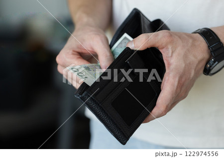 A man takes 100 Polish zlotys from his wallet. Photo concept for an article on economics.  122974556