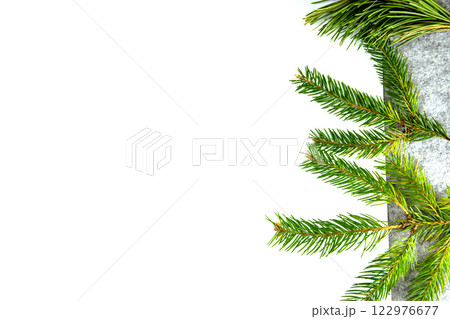 Fresh green pine branches laid on a textured gray surface, showcasing seasonal foliage and natural beauty in a serene arrangement Fresh green pine branches laid on a textured gray surface, showcasing seasonal foliage and natural beauty in a serene arrangement 122976677