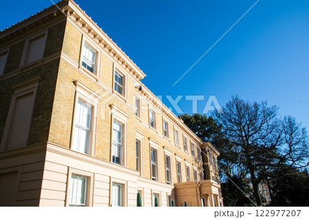 真っ青な快晴の空の下で明るい日差しを浴びるレンガ造りの歴史的建物　ロンドン郊外のキューガーデンにて 122977207