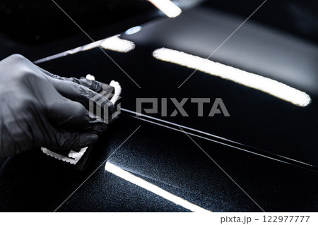 Car wash or detailing studio employee applies ceramic or graphene coating Car wash or detailing studio employee applies ceramic or graphene coating 122977777