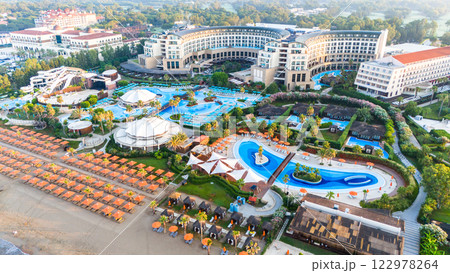 Aerial view of a luxury beachfront resort with pools, a water park, and a private sunbathing area Aerial view of a luxury beachfront resort with pools, a water park, and a private sunbathing area 122978264