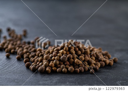 Pile allspice or Jamaican pepper on a black kitchen table, selective focus. Pile allspice or Jamaican pepper on a black kitchen table, selective focus. 122979363