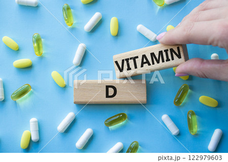 Vitamin D symbol. Concept word Vitamin D on wooden blocks. Beautiful blue background with pills. Doctor hand. Medicine and Vitamin D concept. Copy space 122979603
