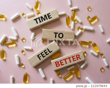 Time to feel better symbol. Concept word Time to feel better on wooden blocks. Beautiful pink background with pills. Health concept. Copy space Time to feel better symbol. Concept word Time to feel better on wooden blocks. Beautiful pink background with pills. Health concept. Copy space 122979643
