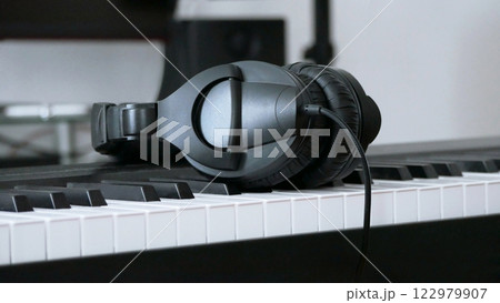 Headphones lie on the keys of the synthesizer. Headset on an electronic piano. Music creation and sound recording concept 122979907