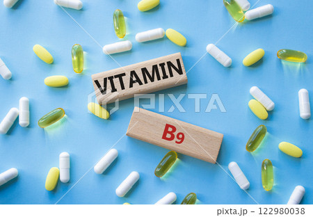 Vitamin B9 symbol. Concept word Vitamin B9 on wooden blocks. Beautiful blue background with pills. Medicine and Vitamin B9 concept. Copy space Vitamin B9 symbol. Concept word Vitamin B9 on wooden blocks. Beautiful blue background with pills. Medicine and Vitamin B9 concept. Copy space 122980038