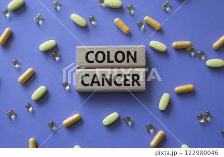Colon Cancer symbol. Concept word Colon Cancer on wooden blocks. Beautiful purple background with pills. Medicine and Colon Cancer concept. Copy space 122980046