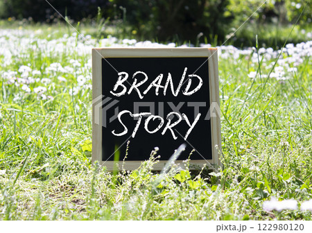 Brand Story symbol. Blackboard with words Brand Story. Beautiful meadow background. Business and Brand Story concept. Copy space. 122980120