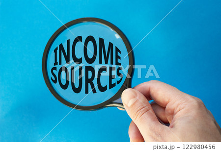 Income Sources symbol. Magnifying Glass with Concept word Income Sources. Beautiful blue background. Businessman hand. Business and Income Sources concept. Copy space Income Sources symbol. Magnifying Glass with Concept word Income Sources. Beautiful blue background. Businessman hand. Business and Income Sources concept. Copy space 122980456