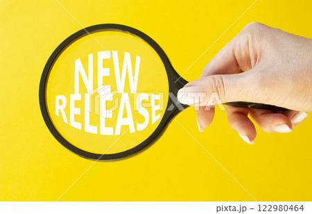 New Release symbol. Concept word New Release on magnifying glass. Beautiful yellow background. Businessman hand. Business and New Release concept. Copy space. 122980464
