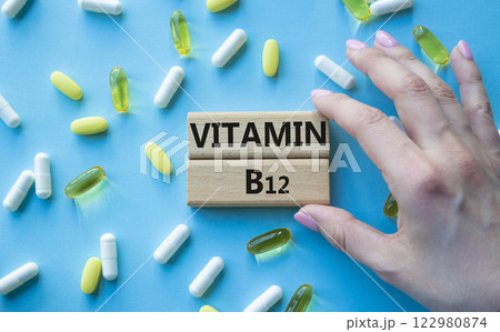 Vitamin B12 symbol. Concept word Vitamin B12 on wooden blocks. Beautiful blue background with pills. Doctor Hand. Medicine and Vitamin B12 concept. Copy space Vitamin B12 symbol. Concept word Vitamin B12 on wooden blocks. Beautiful blue background with pills. Doctor Hand. Medicine and Vitamin B12 concept. Copy space 122980874