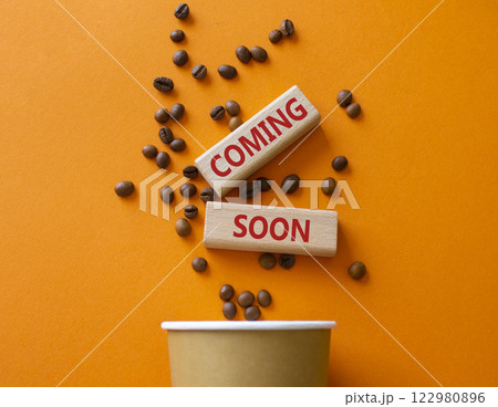 Coming Soon symbol. Concept word Coming Soon on wooden blocks. Beautiful orange background with coffee cup. Business and Coming Soon concept. Copy space 122980896