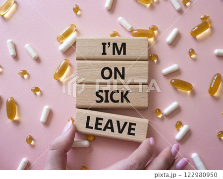 Sick leave symbol. Concept word I am on sick leave on wooden blocks. Businessman hand. Beautiful pink background with pills. Medicine and I am on sick leave concept. Copy space Sick leave symbol. Concept word I am on sick leave on wooden blocks. Businessman hand. Beautiful pink background with pills. Medicine and I am on sick leave concept. Copy space 122980950