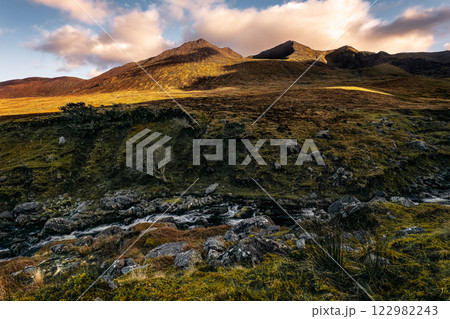 Stunning landscape showcasing rugged mountains illuminated by warm sunlight, with a clear river winding through lush greenery in the Highlands, capturing the beauty of nature at dusk. Stunning landscape showcasing rugged mountains illuminated by warm sunlight, with a clear river winding through lush greenery in the Highlands, capturing the beauty of nature at dusk. 122982243