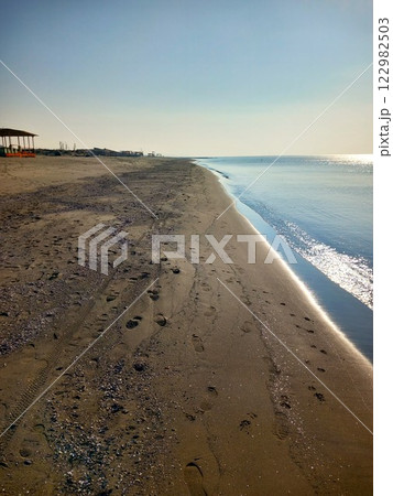 deserted beach with footprints in the sand and the edge of the blue sea deserted beach with footprints in the sand and the edge of the blue sea 122982503