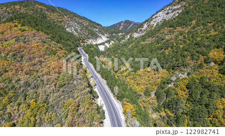 Asphalt road between the mountains and green, yellow trees. Nature landscape in the autumn Asphalt road between the mountains and green, yellow trees. Nature landscape in the autumn 122982741