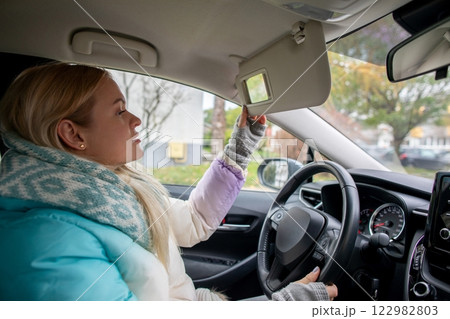 A Young Woman is Adjusting the Sun Visor in her Car while Enjoying the Daylight Hours A Young Woman is Adjusting the Sun Visor in her Car while Enjoying the Daylight Hours 122982803