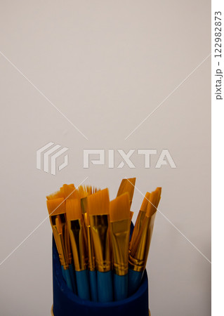 A Beautiful Array of Colorful Paintbrushes Displayed in a Holder Against a Neutral Wall Background 122982873