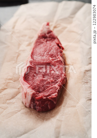 Raw new york sirloin steak on parchment paper warming up before cooking 122983074